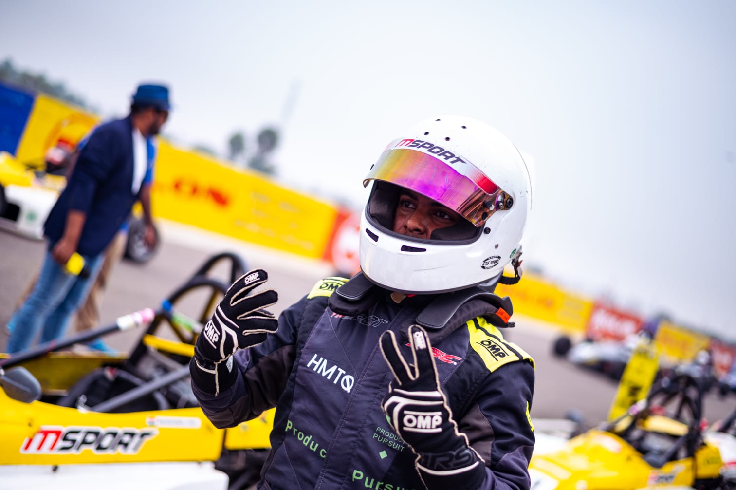 Avi wearing his helmet beside a yellow formula car